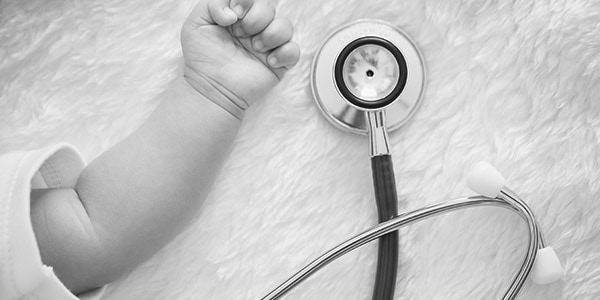 baby's hand next to stethoscope